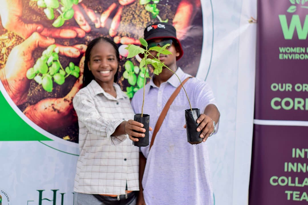 Two young people holding up tree seedlings in nursery bags